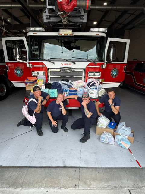 crew in front of fire truck with school supplies 